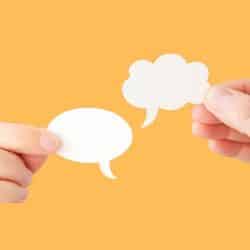 Manos sosteniendo burbujas de diálogo, simbolizando conexión y conversación